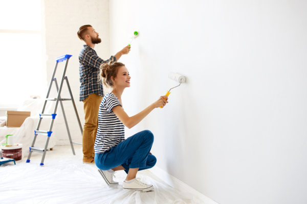 Man och kvinna målar vägg med vit färg